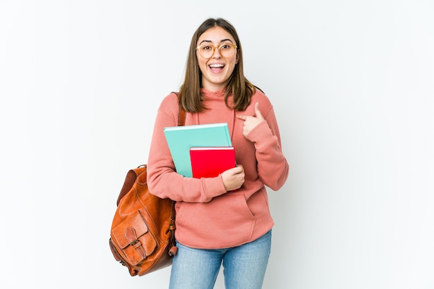 Mulher jovem estudante surpresa apontando com o dedo, sorrindo amplamente