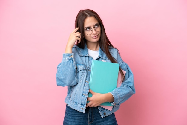 Mulher jovem estudante ucraniana isolada em fundo rosa com dúvidas e pensando