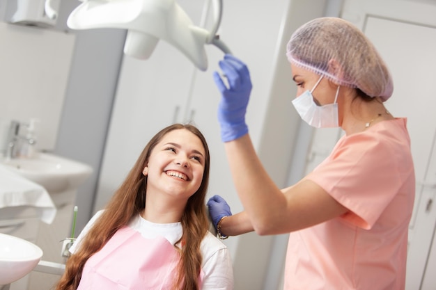 Mulher jovem europeia sendo examinada pelo estomatologista Mulher de beleza sentada na cadeira médica enquanto o dentista fixa seus dentes na clínica dentária O dentista examina os dentes do paciente