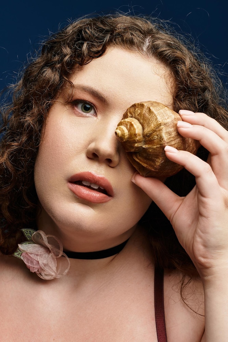 Foto mulher jovem exibindo estilo com uma concha em um cenário artístico interior