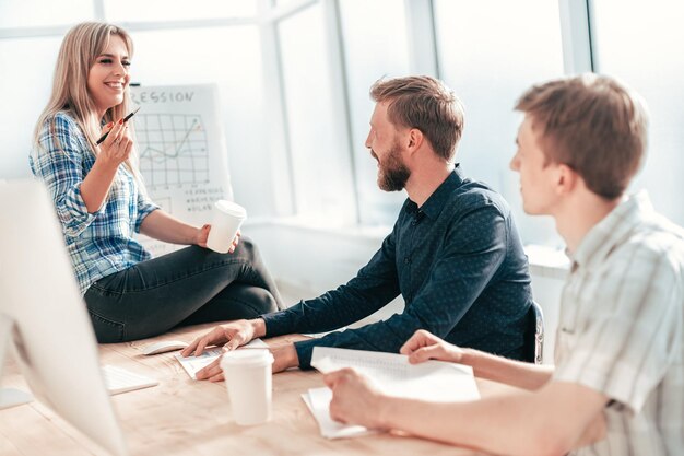 Mulher jovem explicando aos colegas suas idéias. o conceito de trabalho em equipe