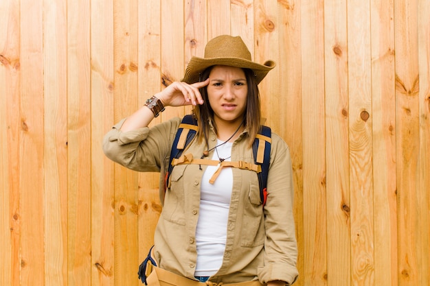 Mulher jovem explorador latino contra o fundo da parede de madeira