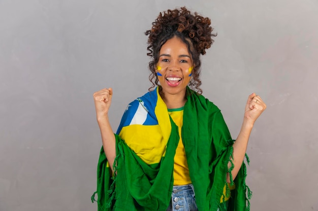 Mulher jovem fã de futebol brasileiro comemorando o time de futebol do Brasil vibrante