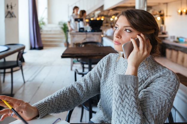 Mulher jovem falando ao telefone em um café