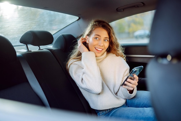 Mulher jovem falando ao telefone no banco de trás do carro Conceito de blog de tecnologia de negócios