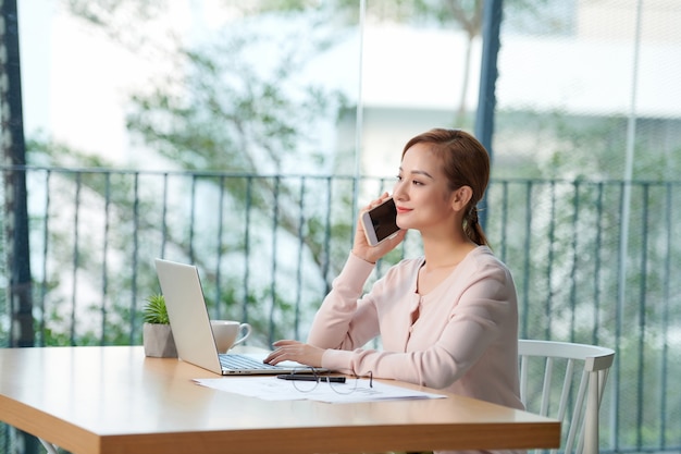 Mulher jovem falando ao telefone no local de trabalho