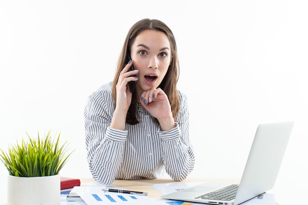 Mulher jovem falando ao telefone no local de trabalho