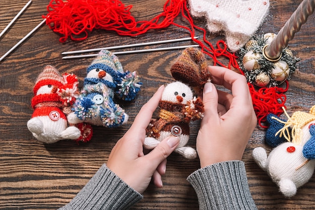 Mulher jovem fazendo brinquedos de natal feitos à mão em uma mesa de madeira