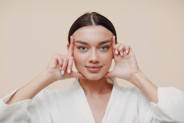 Mulher jovem fazendo ginástica facial de auto massagem e exercícios de rejuvenescimento