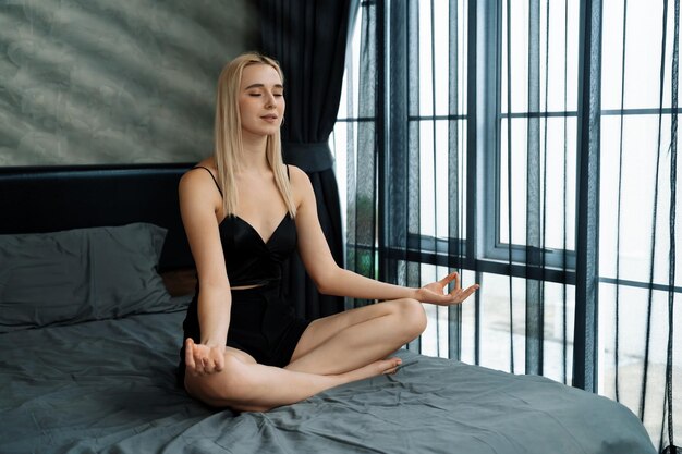 Mulher jovem fazendo ioga matinal e meditação em seu quarto Blithe