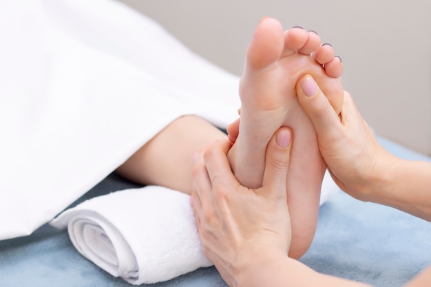 Mulher jovem fazendo massagem nos pés no salão de beleza, vista de perto