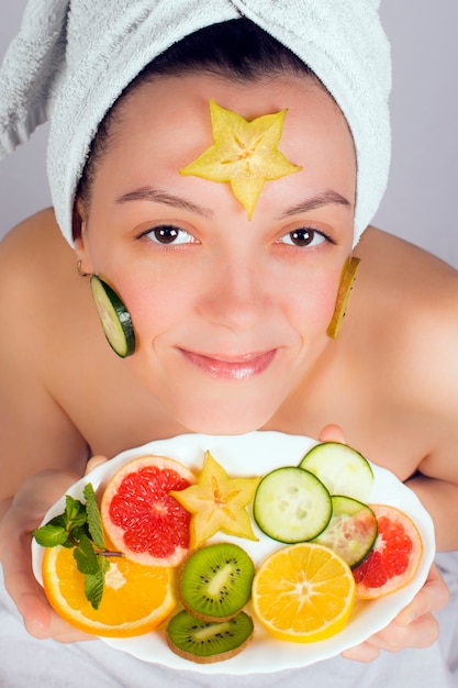 Mulher jovem fazendo um tratamento de beleza com frutas no rosto