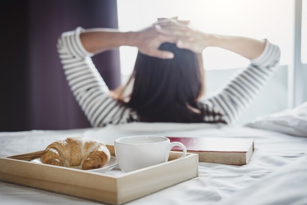 Mulher jovem felicidade na cama com um livro velho