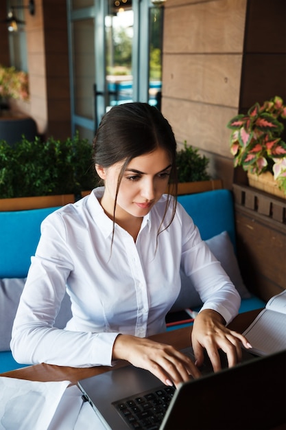 Mulher jovem feliz bem sucedida trabalhando no laptop no café ao ar livre. Retrato de empresária sorridente