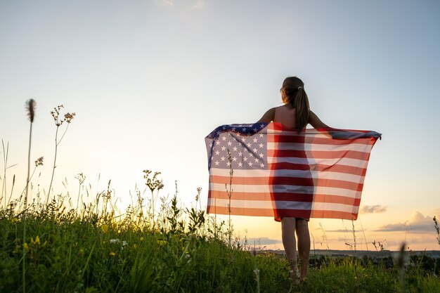 Mulher jovem feliz com a bandeira nacional dos estados unidos na mão