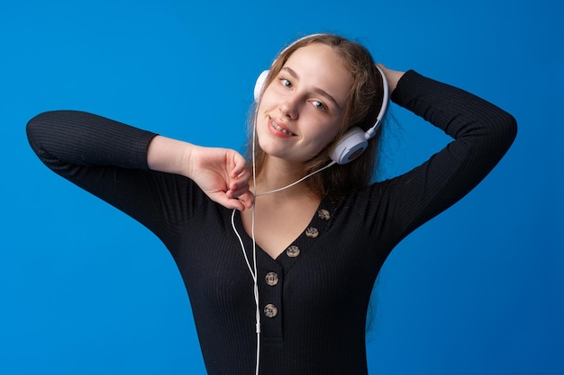 Mulher jovem feliz com fones de ouvido em um fundo azul