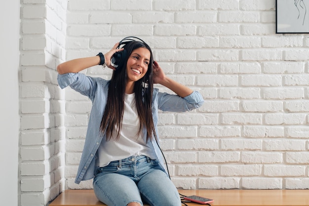 Mulher jovem feliz com fones de ouvido ouvindo música com o telefone inteligente