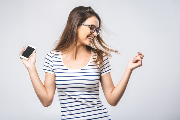 Mulher jovem feliz com fones de ouvido ouvindo música com telefone inteligente