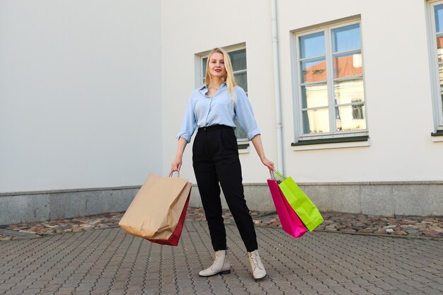 Mulher jovem feliz com sacolas coloridas depois de fazer compras