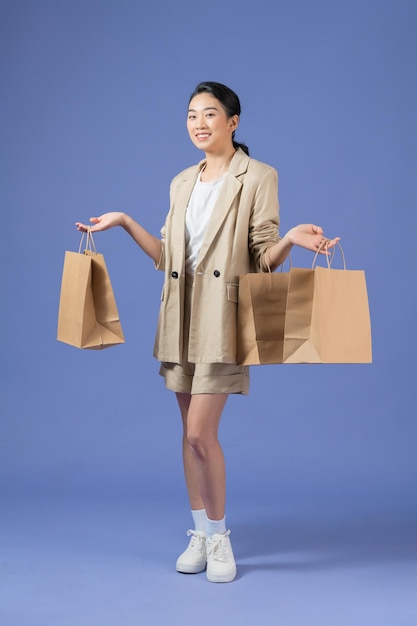 Mulher jovem feliz com sacolas de compras no fundo roxo