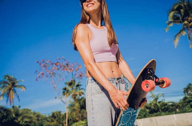 Mulher jovem feliz com skate desfruta de longboard no skatepark