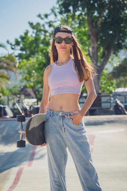 Mulher jovem feliz com skate desfruta de longboard no skatepark