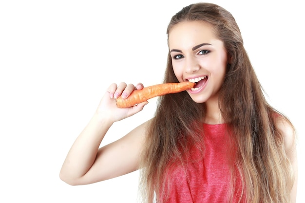 Mulher jovem feliz comendo uma cenoura isolada em branco