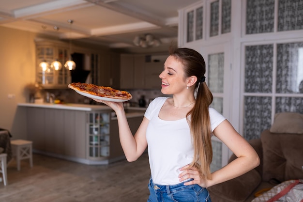 Mulher jovem feliz cozinhando pizza em casa