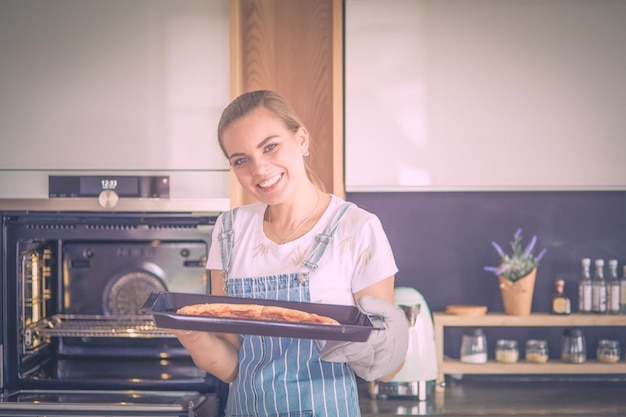 Mulher jovem feliz cozinhando pizza em casa