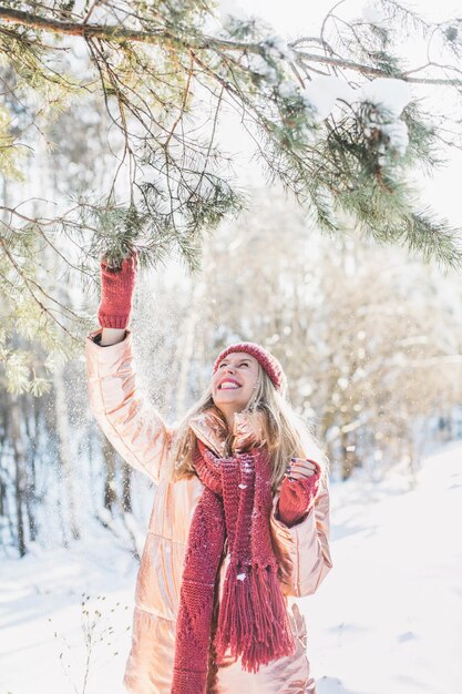 Mulher jovem feliz desfrutando de árvores em um campo coberto de neve no inverno