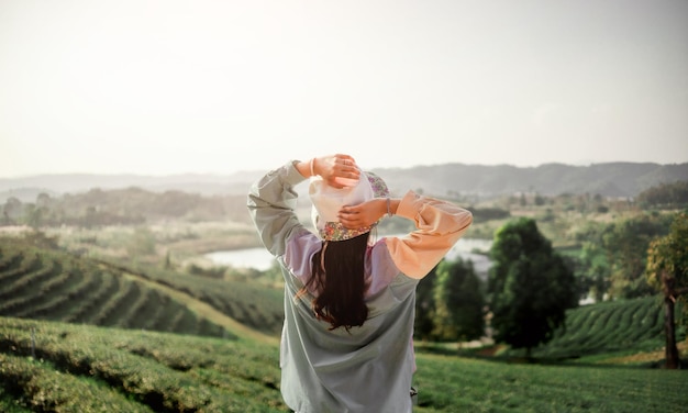 Mulher jovem feliz desfrutando de liberdade com as mãos abertas na montanha Mulher feliz despreocupada respirando Apreciando a vista da natureza no penhasco da montanha Conceito de liberdade ao ar livre viagem vida