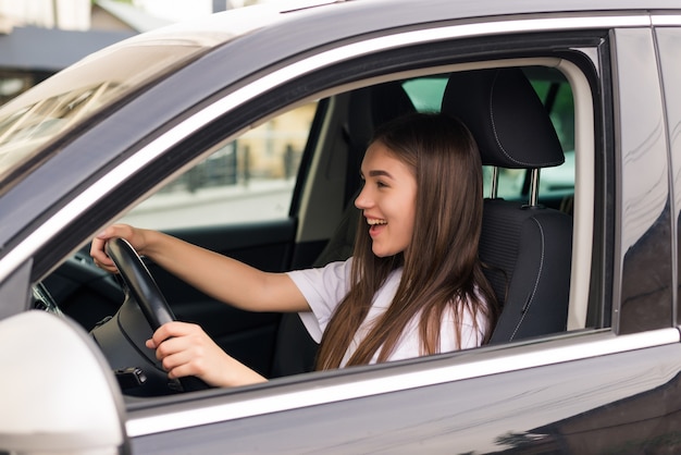 Mulher jovem feliz dirigindo seu carro novo