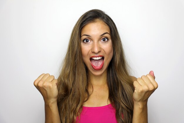 Mulher jovem feliz e bem-sucedida com as mãos levantadas, gritando e comemorando o sucesso