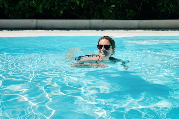 Mulher jovem feliz e bonita aproveitando a piscina de tempo livre. Estilo de vida romântico divertido. Garota em viagem de férias na estância de férias. Viajar juntos. Vista na pessoa adulta feminina relaxe no verão.