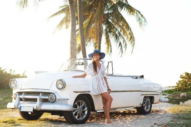 Mulher jovem feliz e carro conversível retrô ao lado da praia na cidade de Varadero