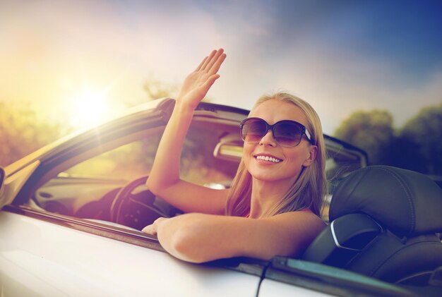 Foto mulher jovem feliz em carro conversível, acenando com a mão