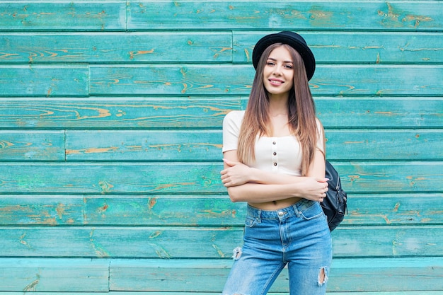 Mulher jovem feliz em jeans azul sobre fundo de madeira ao ar livre