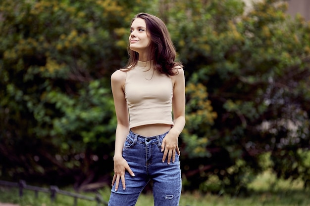 Mulher jovem feliz em jeans caminha no parque