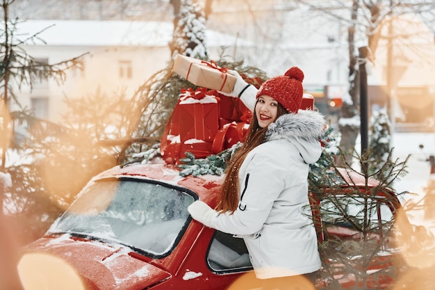 Mulher jovem feliz em pé ao ar livre e comemorando as férias de natal