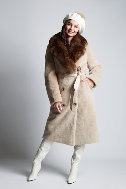 Mulher jovem feliz em pele e chapéu linda garota bruhette no casaco da moda de inverno