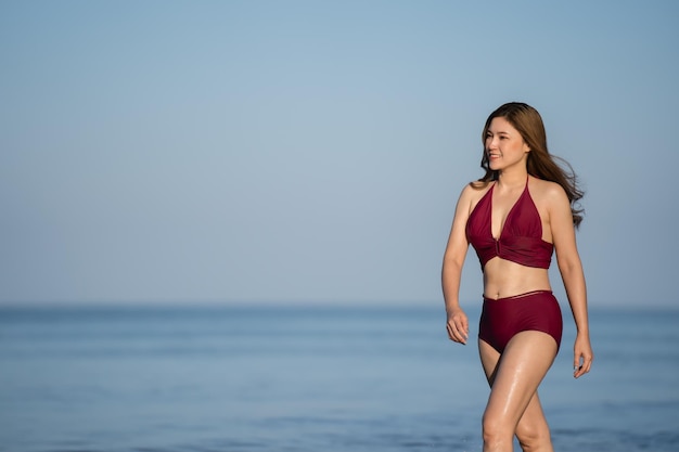 Mulher jovem feliz em traje de banho andando na praia do mar na ilha de Koh Chang Tailândia