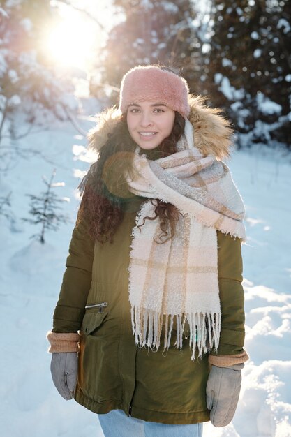 Mulher jovem feliz em trajes de inverno em pé na floresta