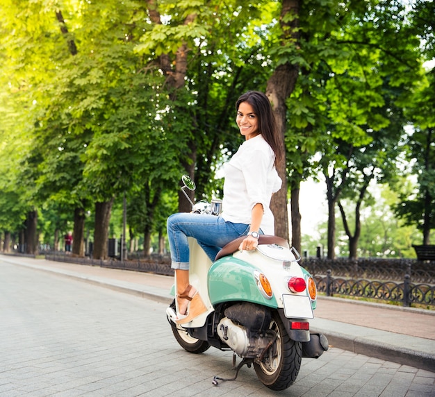 Mulher jovem feliz em uma scooter