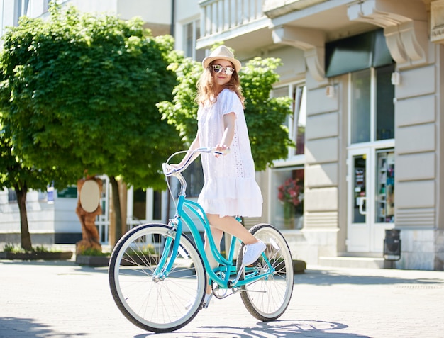 Mulher jovem feliz enjoyfing andar de bicicleta na cidade