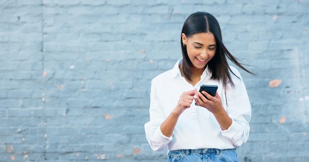 Mulher jovem feliz enviando mensagens de texto em um telefone e rindo na cidade Mulher alegre sorrindo enquanto navega em aplicativos rolando mídias sociais e pesquisando na web on-line enquanto viaja e se desloca na cidade