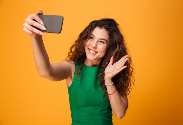 Mulher jovem feliz fazer selfie acenando para os amigos.