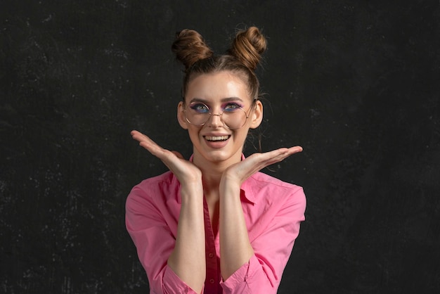 Mulher jovem feliz imaginando com sombras azuis rosa sobre fundo preto Retrato de menina em óculos grandes