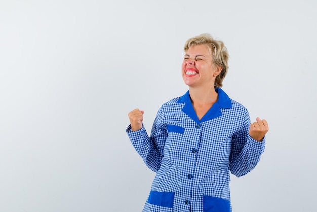 Mulher jovem feliz mostrando os punhos no fundo branco