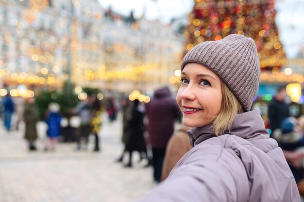 Mulher jovem feliz na rua da cidade, aproveitando o dia de natal