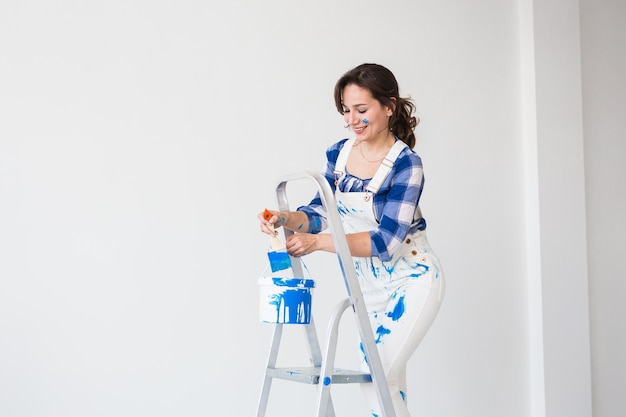 Foto mulher jovem feliz pintando a parede em casa com espaço de cópia